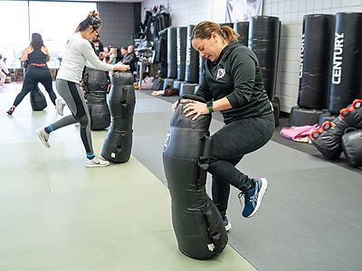 Adults training knee strikes on heavy bags in a Get Fit Done fitness kickboxing class
